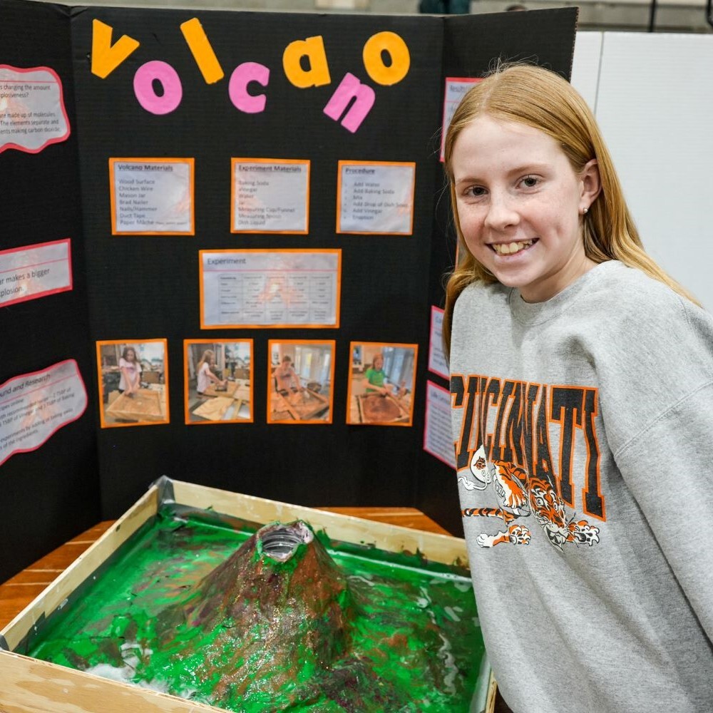 A student stands beside her project on volcanos