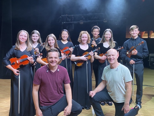 Orchestra students pose for a photo on stage