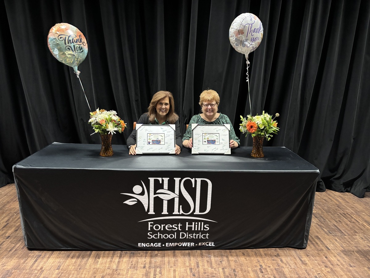Jodie McKinley and Jeanne Ralston post for a photo with flowers, balloons and a thank you card