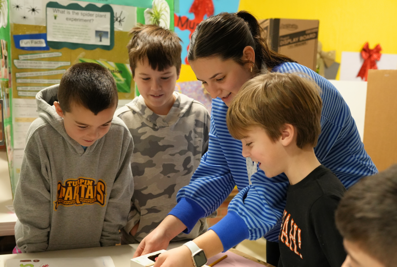a high school student volunteer completes an activity with students