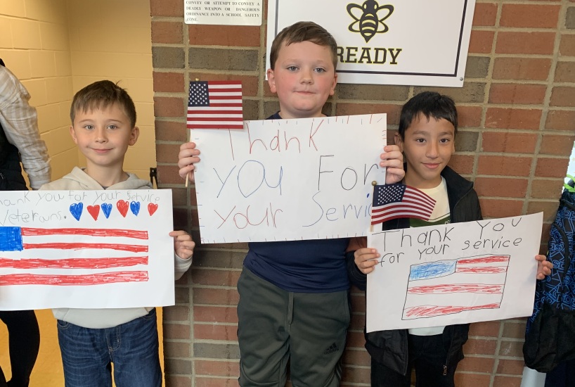 students hold signs in honor of Veterans Day